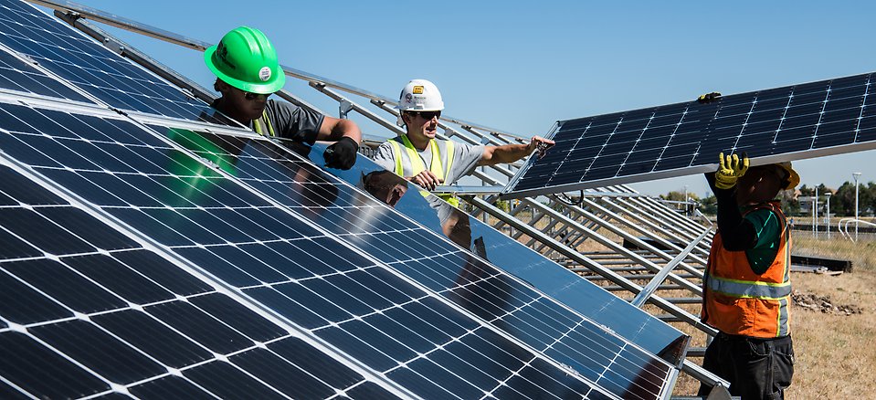 Arbetare installerar solceller i en solcellsanläggning